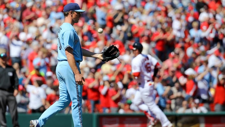 Toronto Blue Jays starting pitcher Chris Bassitt tosses the ball in his glove while wearing Toronto's baby blue jersey and pants. 