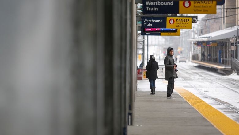 Two passengers wait for a transit train in Calgary.