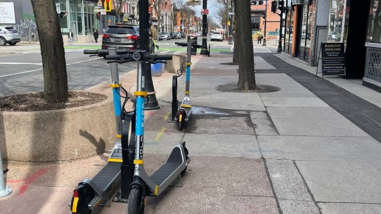 E-scooters are locked along the street. 