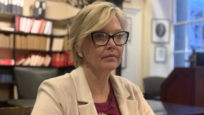 A woman with blond hair and glasses in an office.