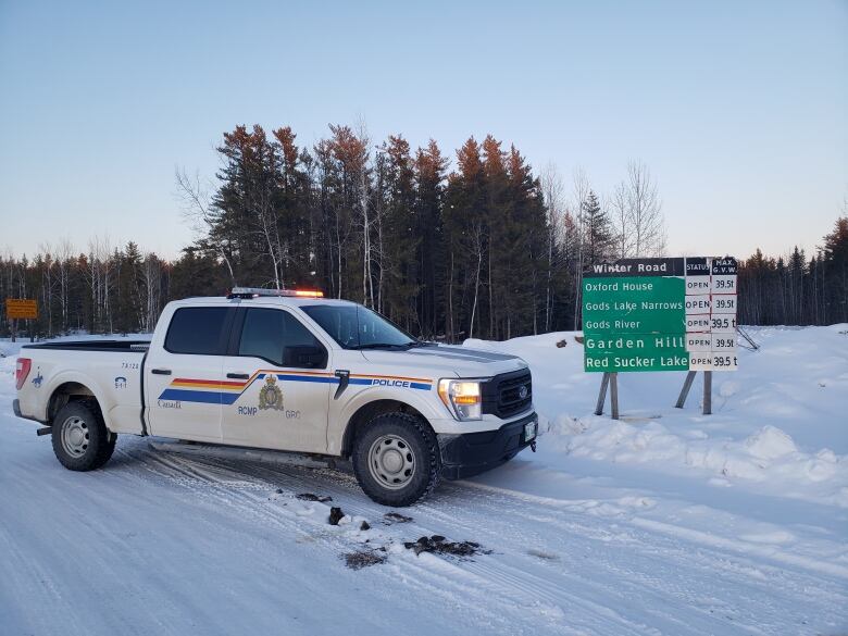 An RCMP truck is parked next to road signs outside of several northern Manitoba First Nation communities.