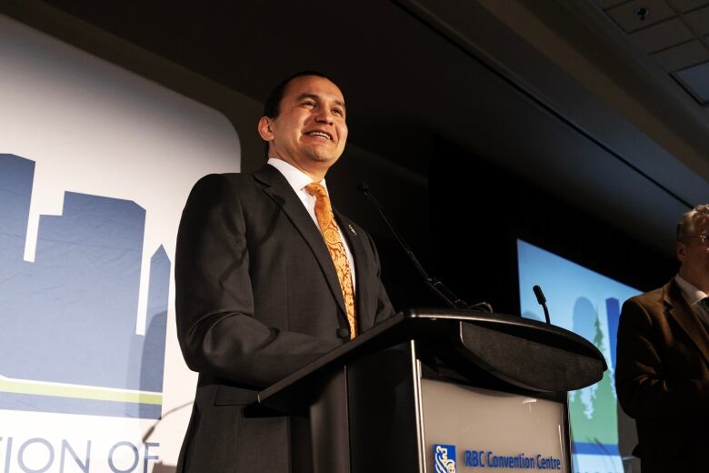 Smiling man stands behind podium.