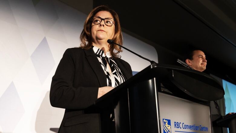 Woman with serious expression stands at a podium.