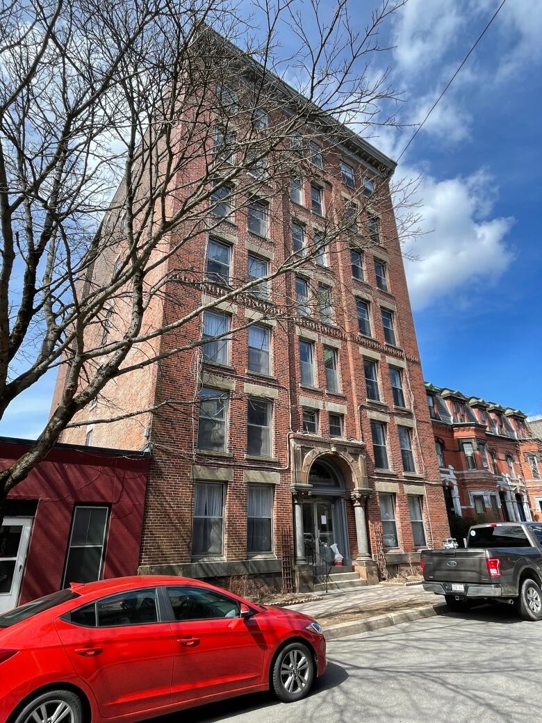 A tall brick apartment building with a red car parked in front of it