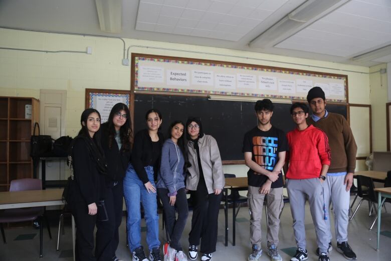 A group of eight teenagers posing in front of the camera.