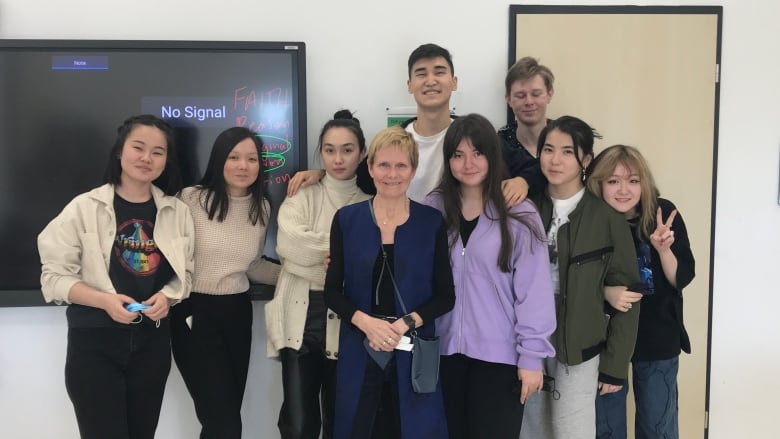 Ingrid Morton stands in her Gr. 11 English classroom surrounded by high school students in Almaty, Kazakhstan.