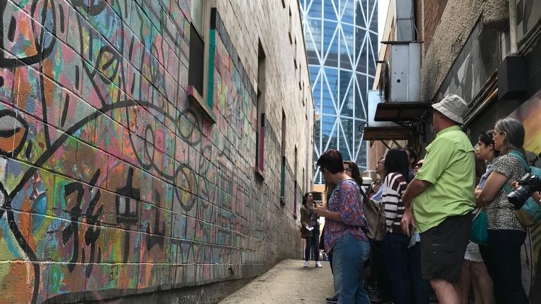 People look at a wall with graffiti on it.