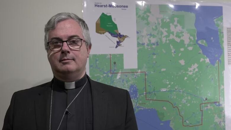 Bishop Tremblay standing in front of a map