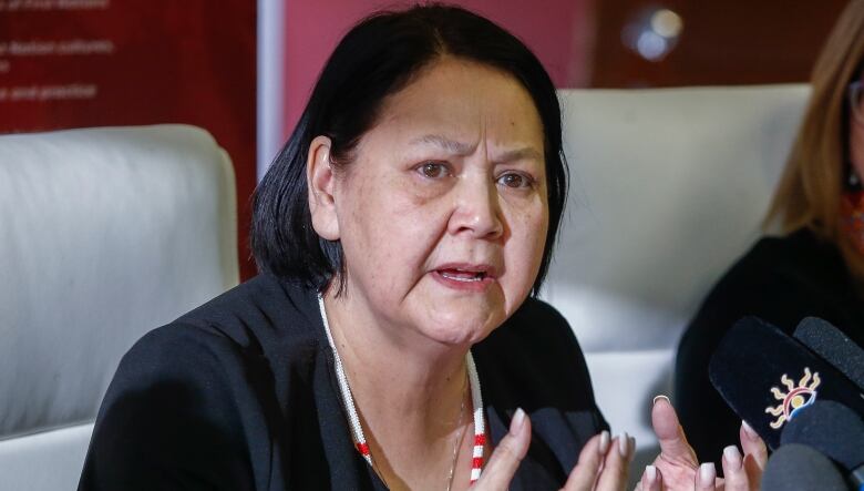 A woman seated in front of microphones.