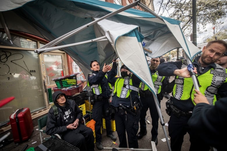 Vancouver police officers form a line to push back protesters and advocates while city employees work to dismantle tents along East Hastings in the downtown Eastside neighbourhood of Vancouver, British Columbia on Wednesday, April 5, 2023. 