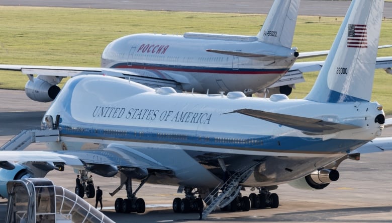 Two airliners sit side-by-side on an airport's tarmac. 