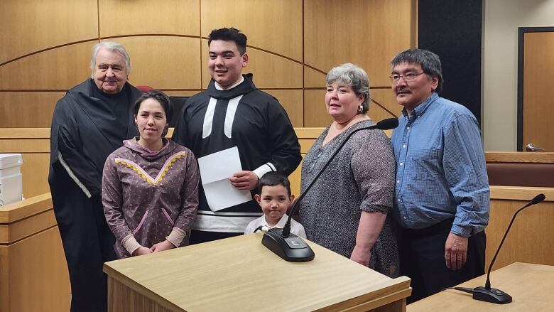 A group of smiling people stand in front of a lectern.