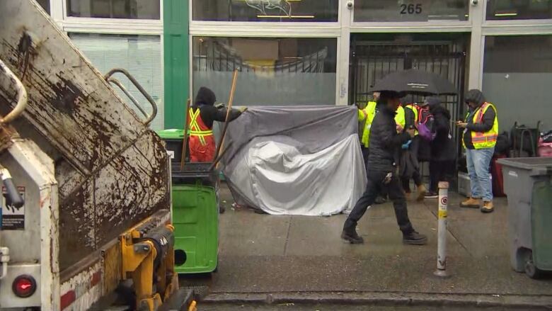 City workers are seen removing a tent from East Hastings Street, Thursday April 6, 2023.