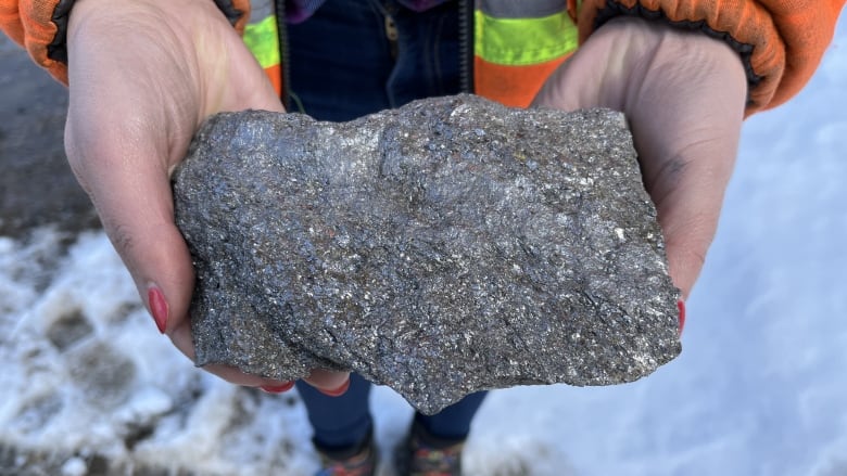 Someone holds a rock containing graphite ore.