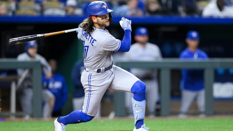 A baseball player swings his bat as he hits a home run.