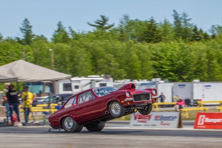 A drag racing car is shown with its back two wheels on the ground and the front two in the air.