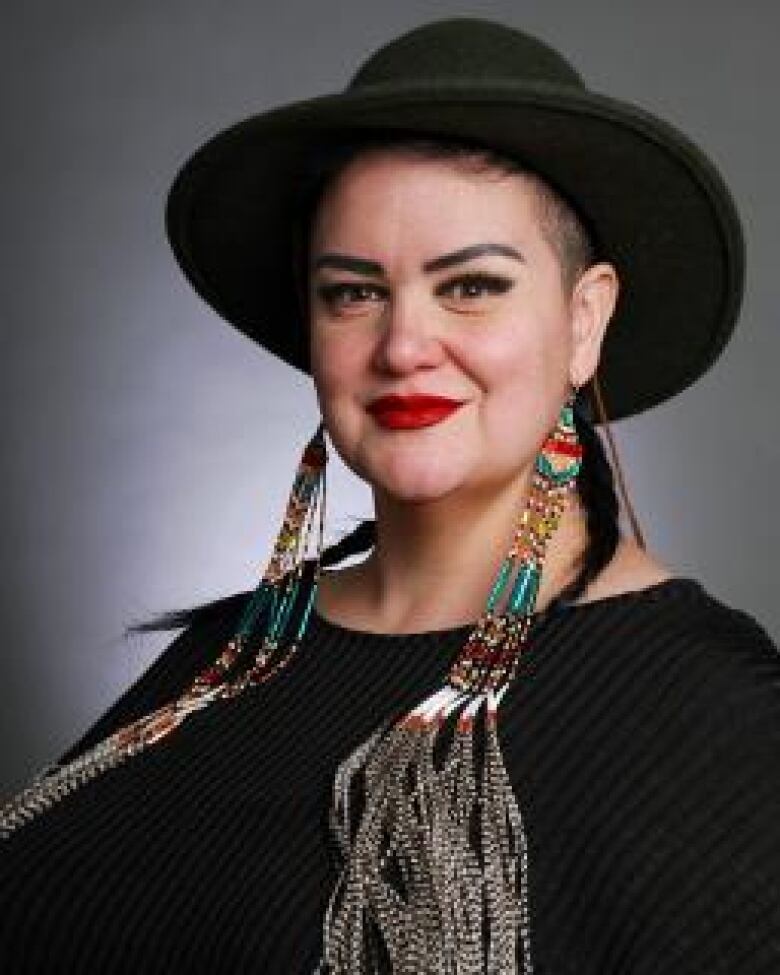 Woman with black hat and black shirt smiles in a headshot.