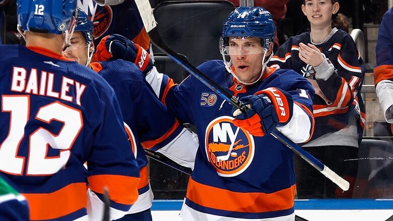 Men's hockey player points to his teammates when celebrating a goal.