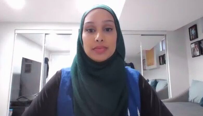 A woman wearing a hijab sitting in a bedroom