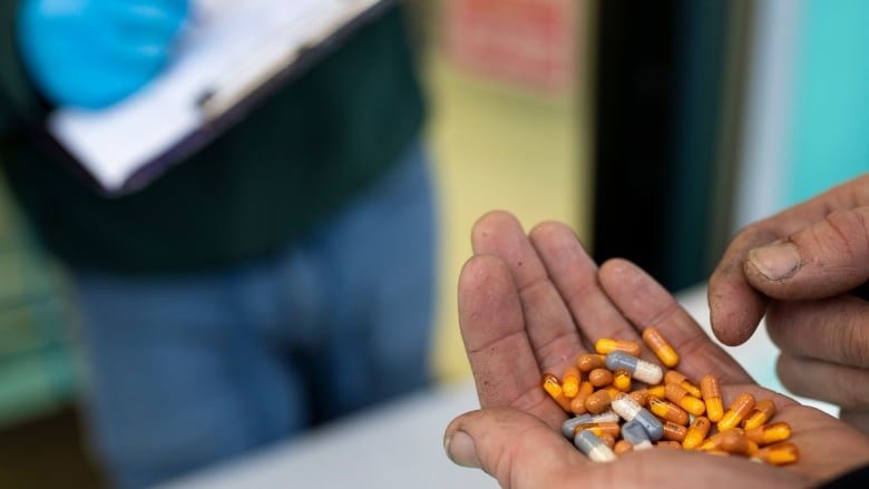 Pills are pictured in a person's hand.