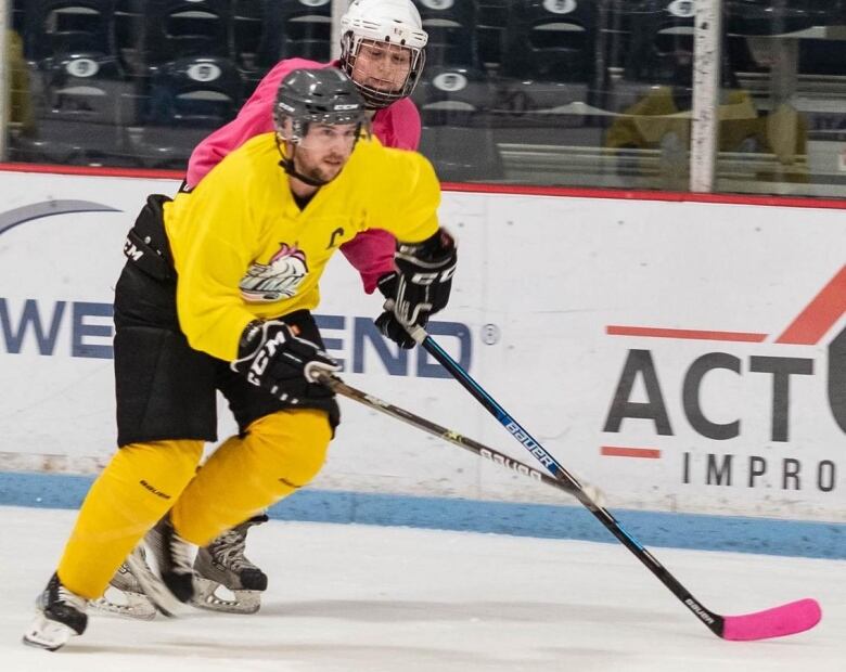 Jay McKellar is skating forward with another hockey player behind him during a hockey game. Both players sticks are visible.