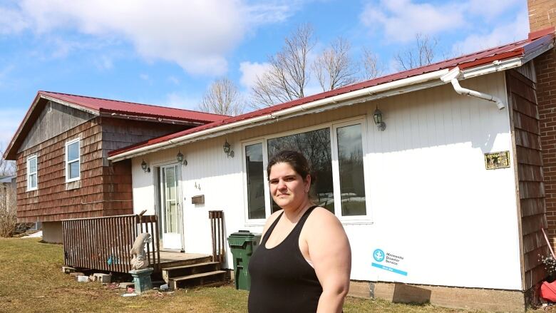 A woman stands in front of a house.