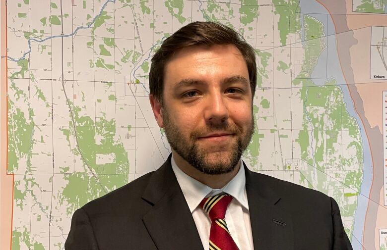 A city councillor poses in front of a map.