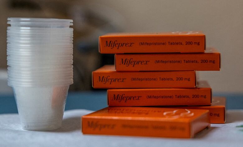 Several packages of a medication are shown next to cups.