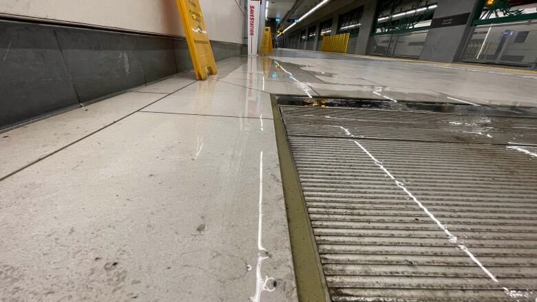 Water flows into a grate at an underground transit station.