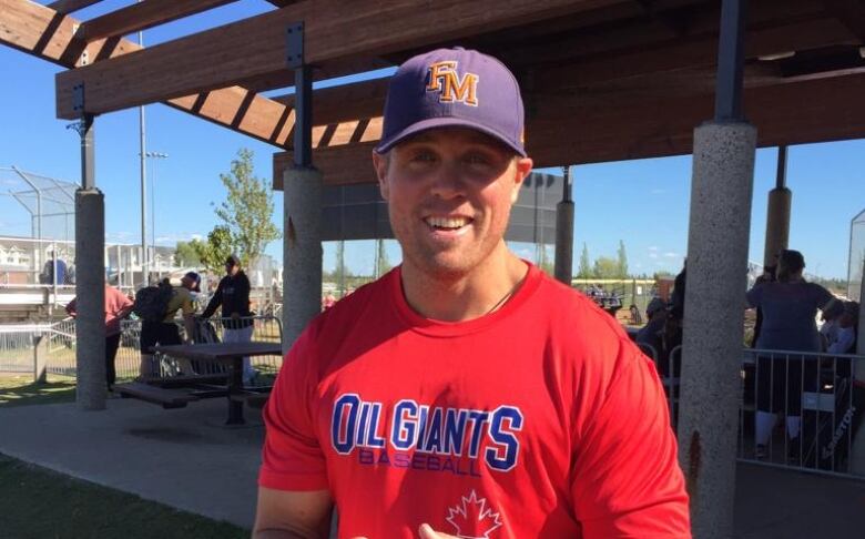 A man in a baseball uniform grins at the camera. 