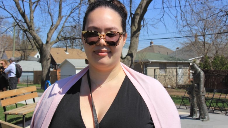 A woman wearing sunglasses with a statue of a police officer in the background.