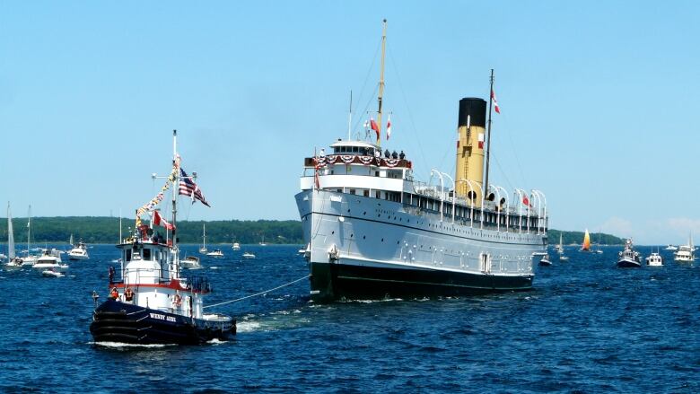 Tugboats pull the Keewatin into Port McNicoll.