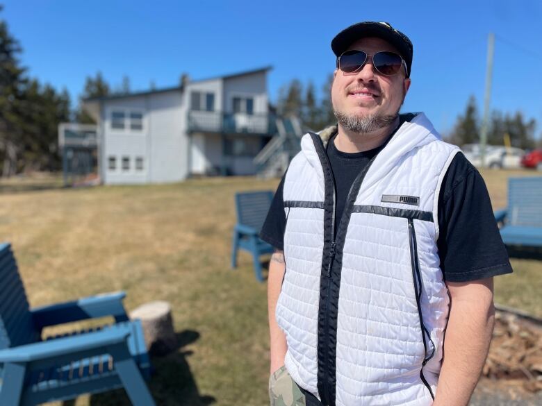 Jason Delio, owner of Cliffside Inn faces the camera with lawn chairs and a building behind him.