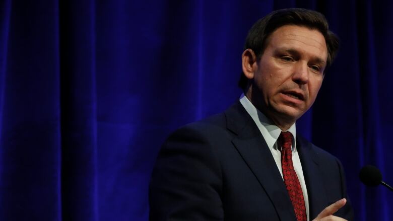 Florida Gov. Ron DeSantis, speaking on a stage, in Hillsdale, Michigan.