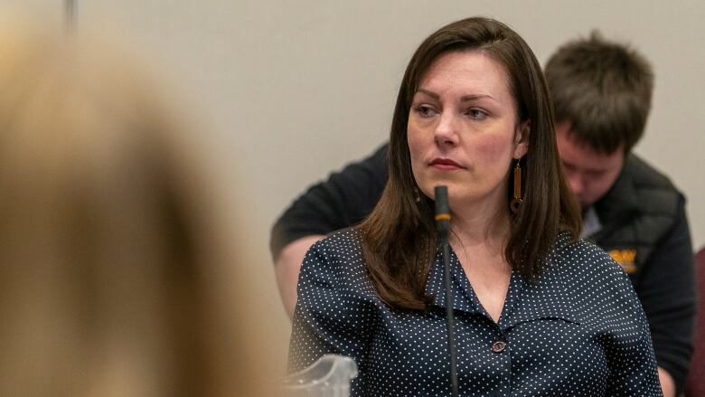 A woman in a black blouse sits at a table. 