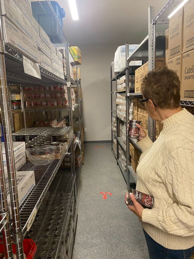 A woman looks out over shelves of boxes of food. 