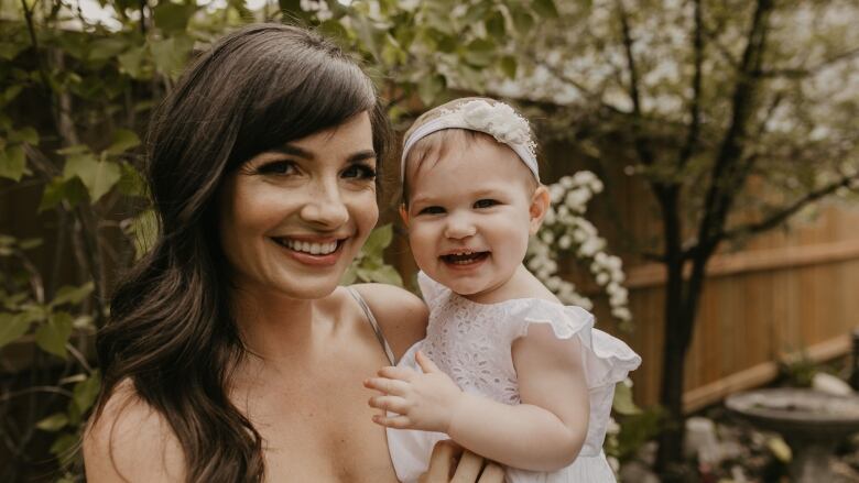 Woman holding child in formal dress.