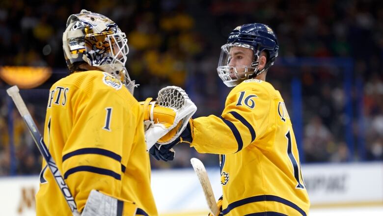 A hockey player bumps fists with his goalie after scoring a goal.