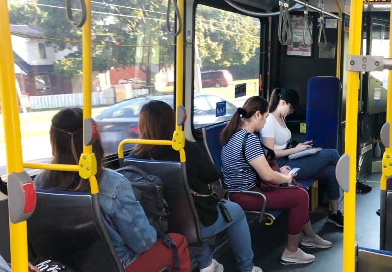 Four people sit on an uncrowded city bus.