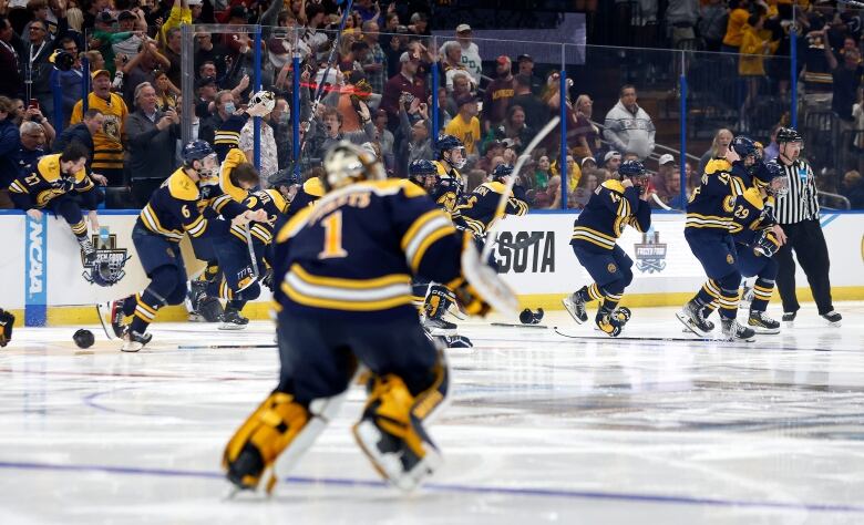 Hockey players storm the ice to celebrate after winning a national title.