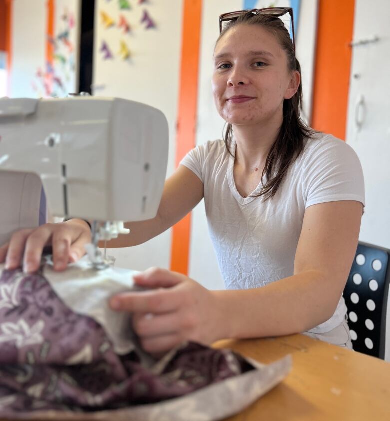 Maris Jacobs sews the collar onto her shirt.