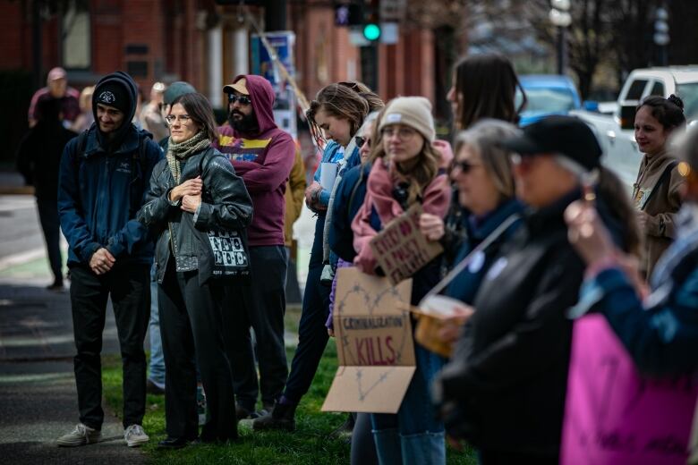 A group of people gather on the street holding signs