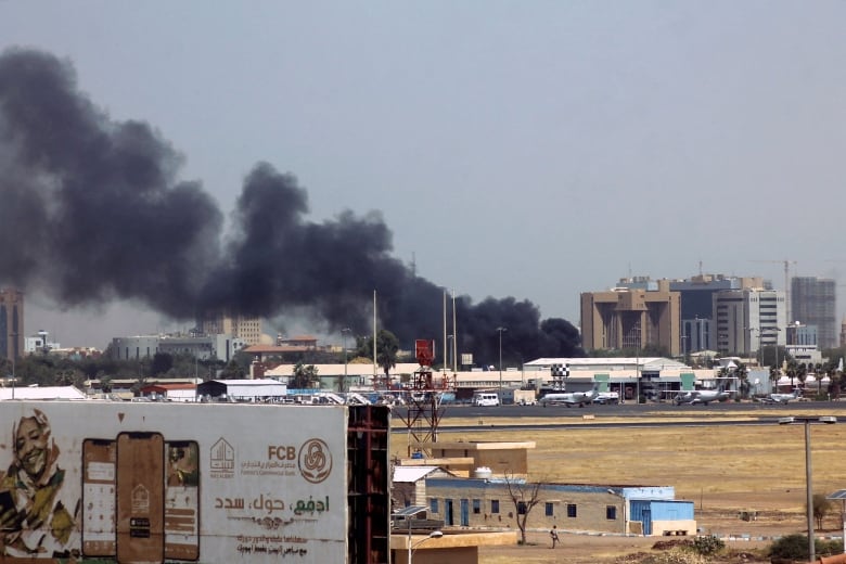 Dark, heavy smoke drifts above buildings.