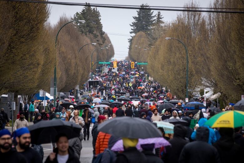 Thousands of people carrying umbrellas line up on a street.