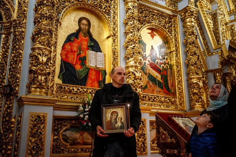 A man holds a painting in a church.