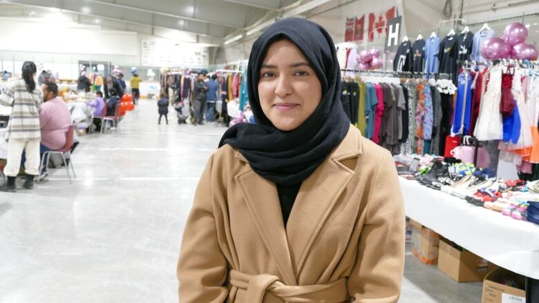 A woman wearing a hijab smiles at the camera.