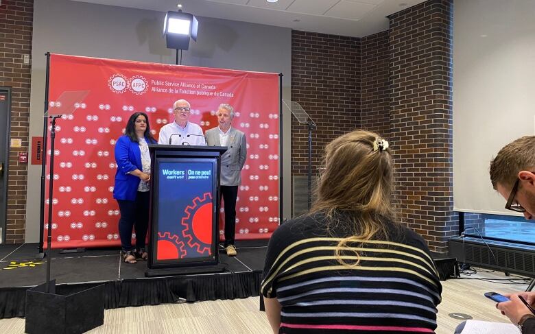 Three union leaders give a news conference.