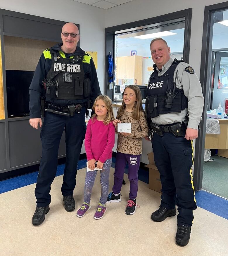 Two young students stand with two police officers.