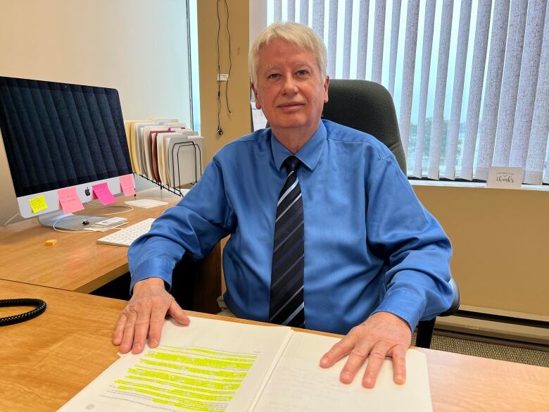 Man in a blue shirt sitting at a desk.