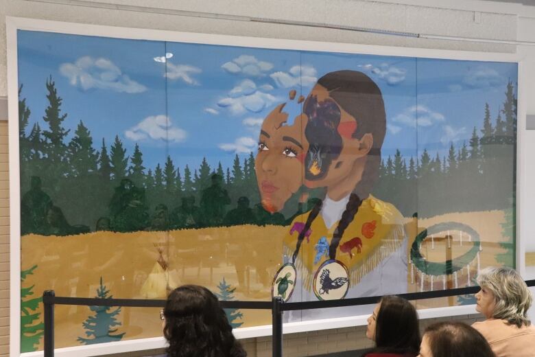 A painted artwork of an Indigenous woman in a field surrounded by green forest and blue sky. The woman's face is coming off to reveal a starry night sky and a campfire.